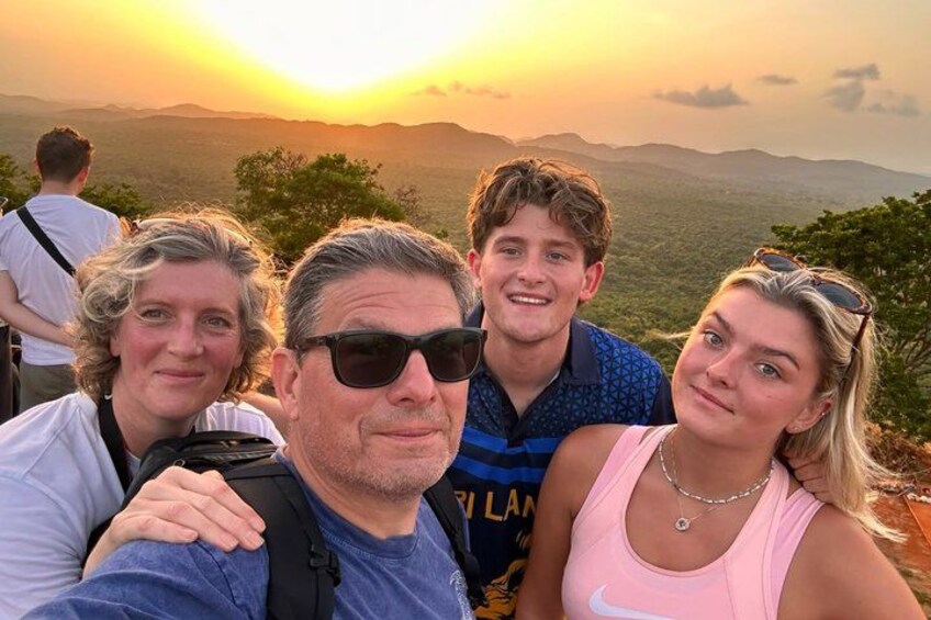 A group of people taking a selfie with a sunset in the background. 3