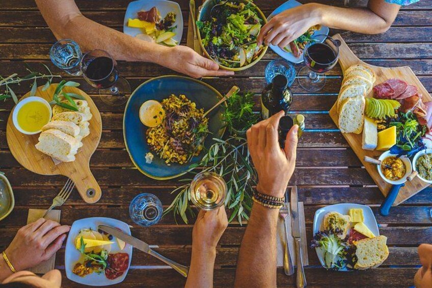 Un groupe de personnes est réuni autour d’une table en bois, où sont servis différents plats et boissons. 4