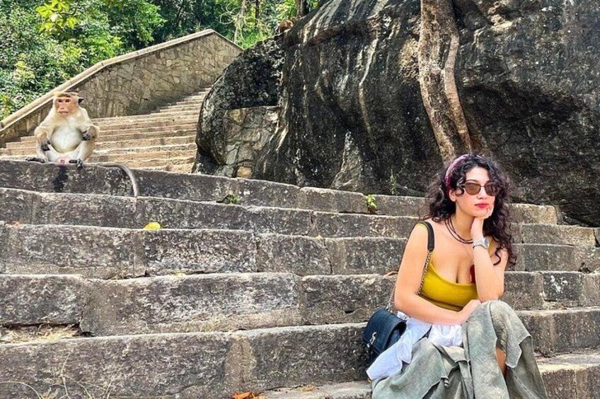 A person sitting on stone steps with a monkey in the background. 5