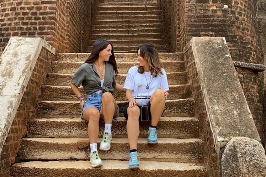 Two people sitting on stone steps in a brick structure. 2