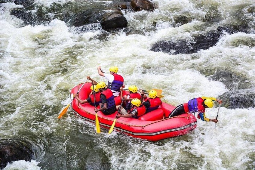 A group of people in a red raft navigating a river with rapids. 2