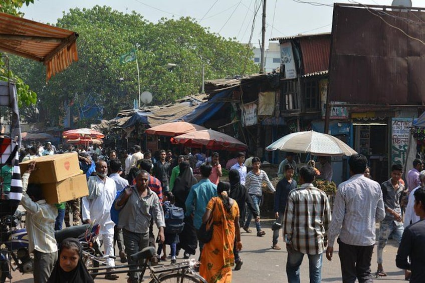 A busy street market with people walking and carrying goods. 3