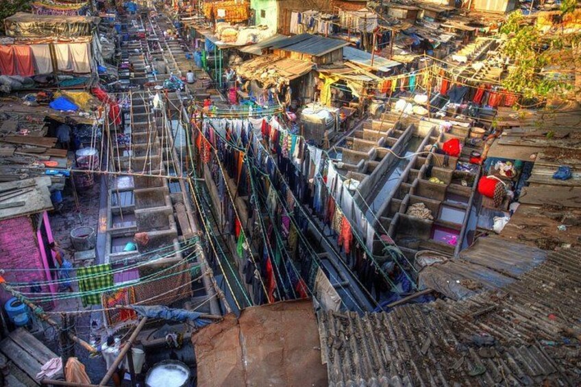 A densely packed slum area with makeshift housing, laundry hanging on lines, and scattered debris. 4