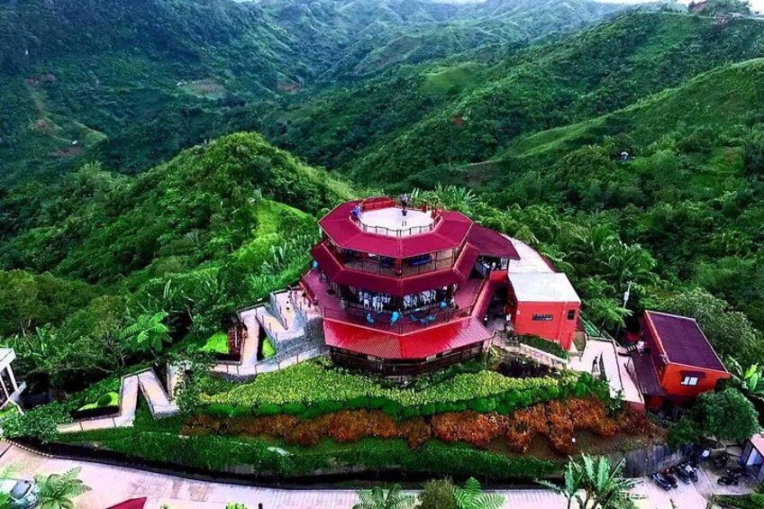 A multi-level red building surrounded by lush green hills. 5