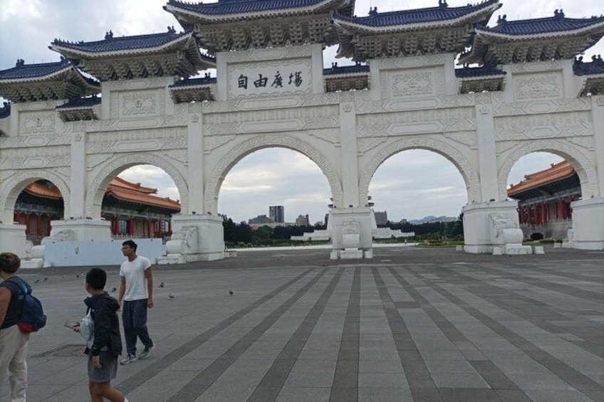A traditional Chinese gate with multiple arches and intricate designs, surrounded by a paved area. 4