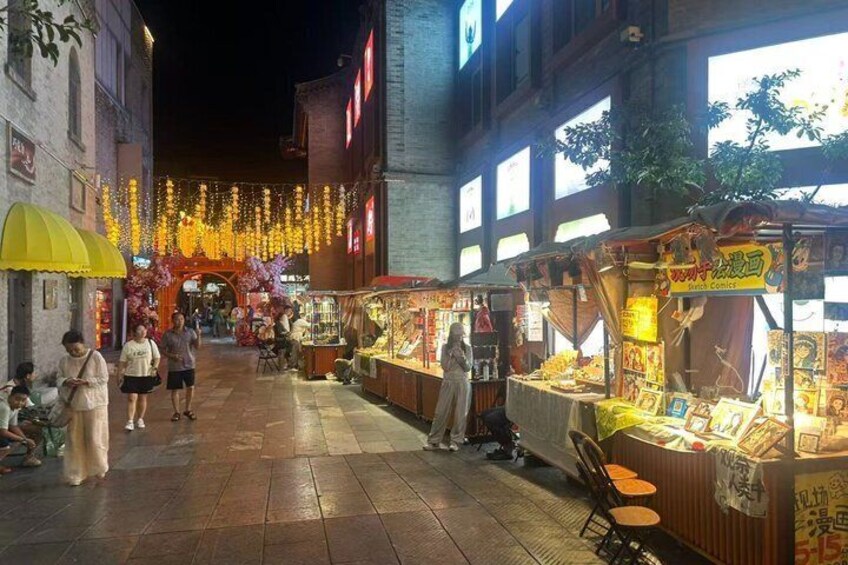 Mercado nocturno callejero con puestos iluminados y gente caminando. 3