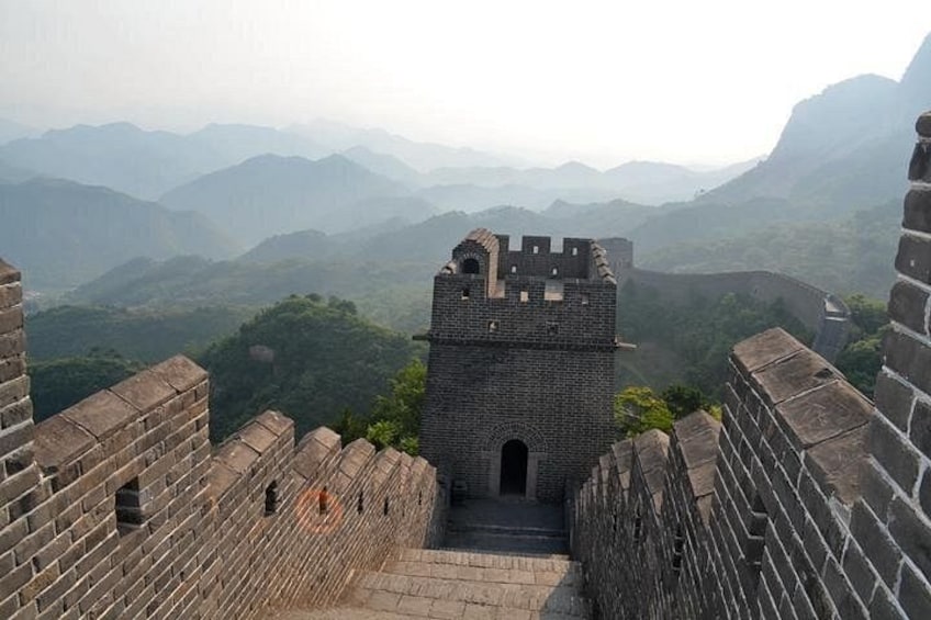 A section of the Great Wall of China with a watchtower, surrounded by mountainous terrain. 2