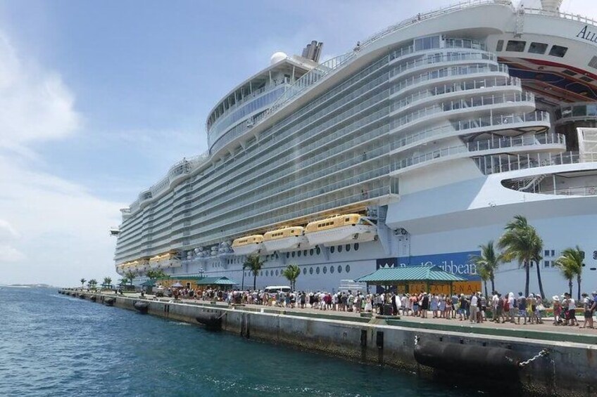 A large cruise ship docked at a port with a crowd of people on the dock. 2
