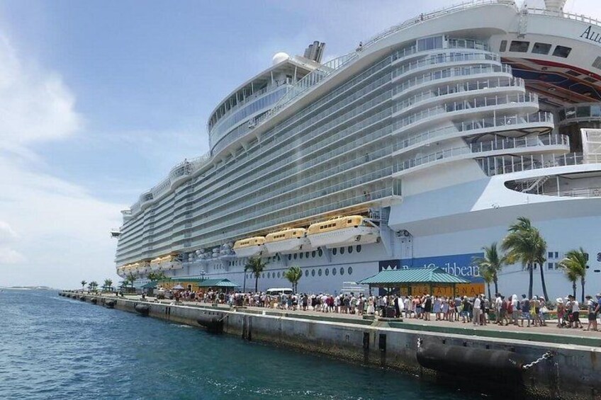 A large cruise ship docked at a port with a crowd of people on the dock. 2