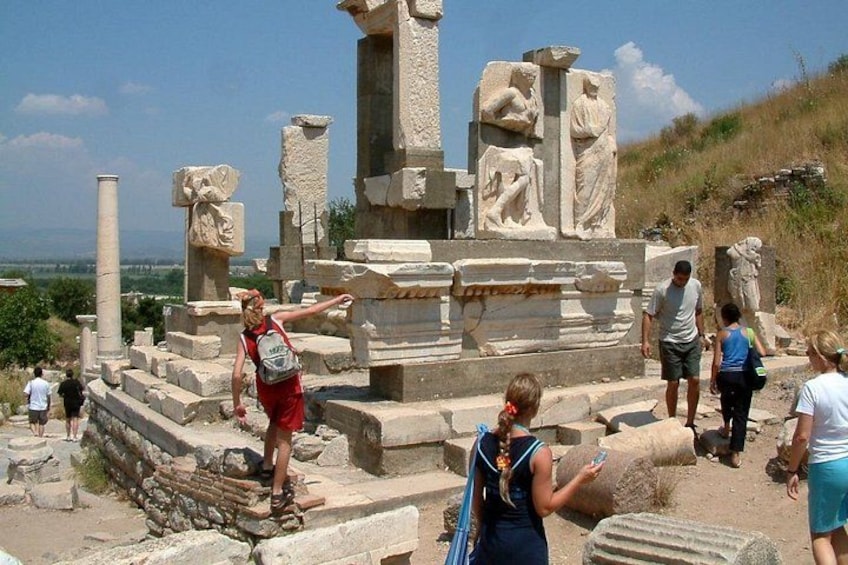 Ancient ruins with columns and statues, tourists exploring the site. 3
