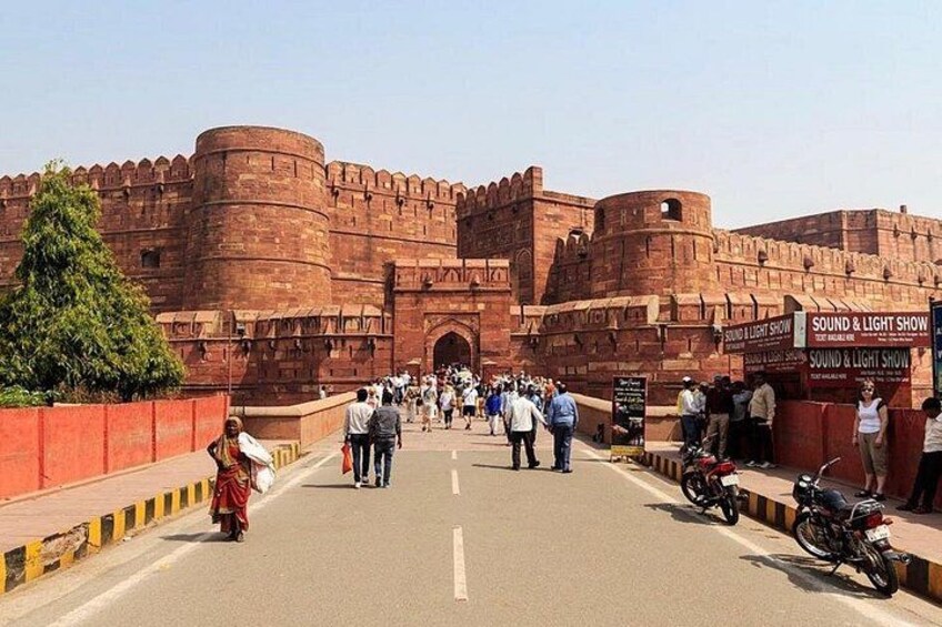 A large red fort with tourists walking in front. 2