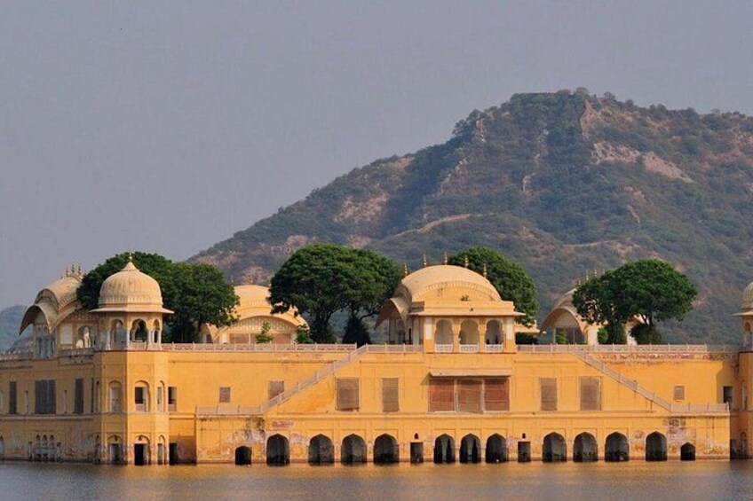 A palace with domed structures and arched walkways by a body of water. 3