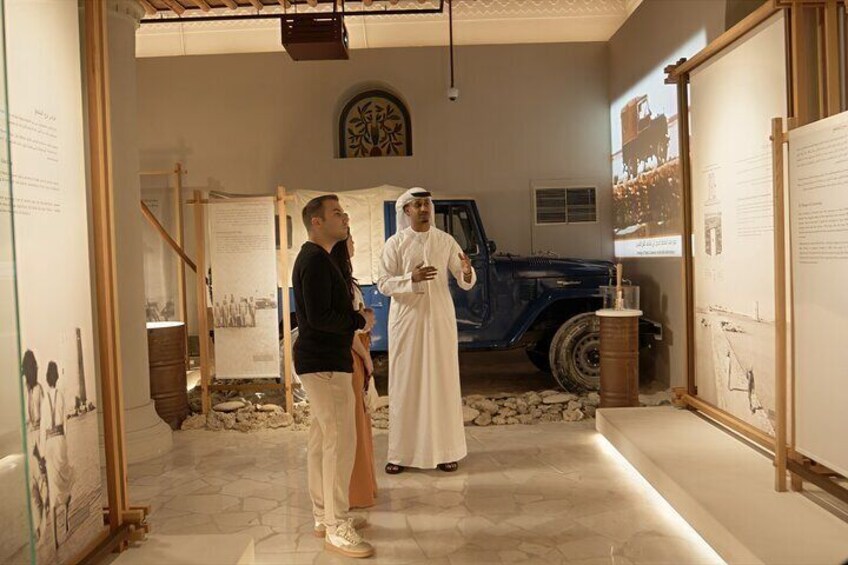 A museum exhibit with a blue truck and a man in traditional attire. 3