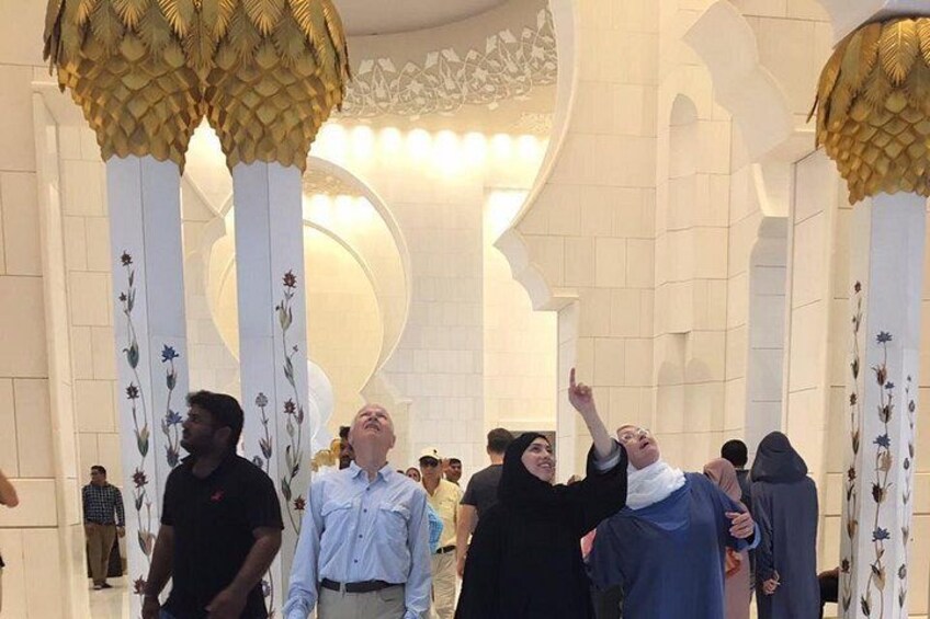 A group of people inside a building with white columns and golden decorative elements. 4