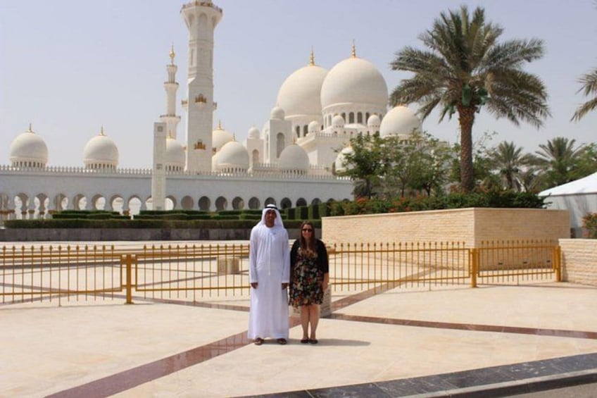 A man and a woman standing in front of a large white mosque with multiple domes and minarets. 2