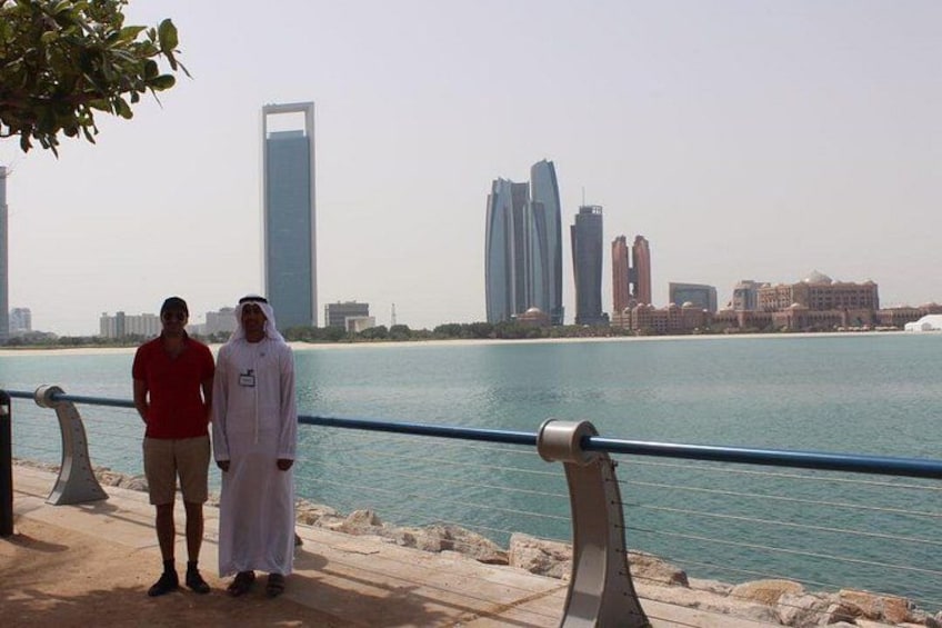 Two people standing by a waterfront with a city skyline in the background. 3