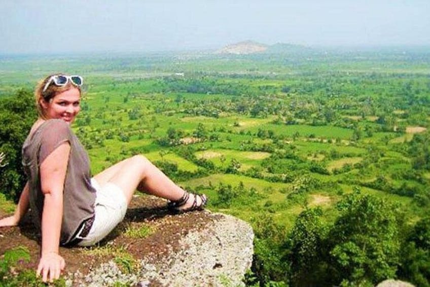 Una persona sentada sobre una roca con vistas a un paisaje verde. 1