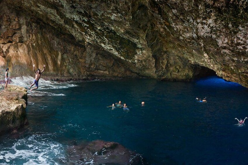 A group of people swimming in a natural cave pool with rocky walls. 1