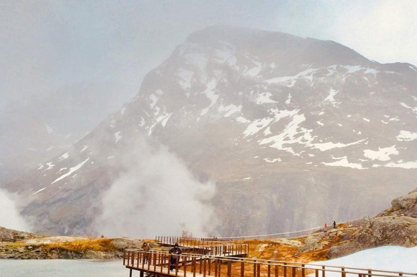 A mountainous landscape with a wooden viewing platform overlooking a body of water. 2