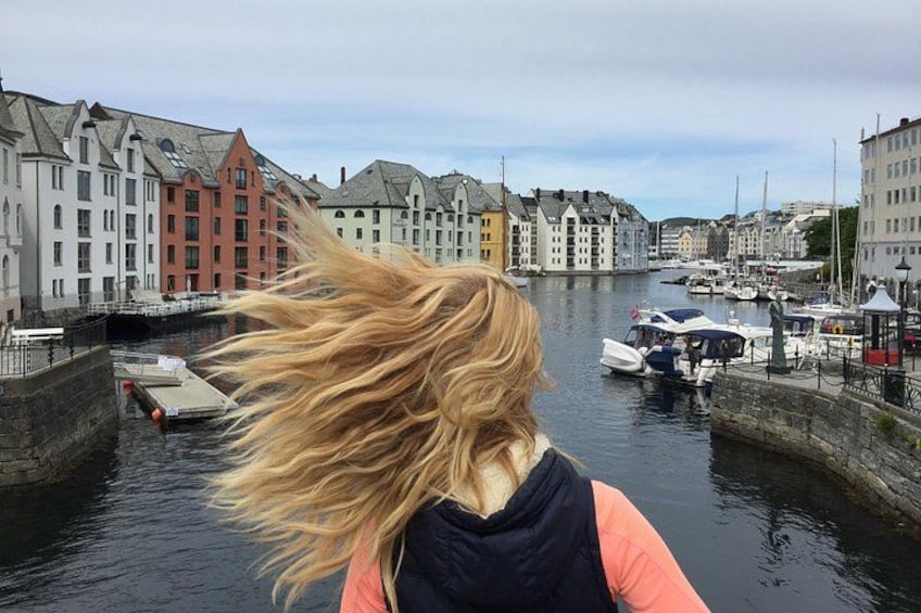 A waterfront with buildings, a boat, and a person with blonde hair. 5