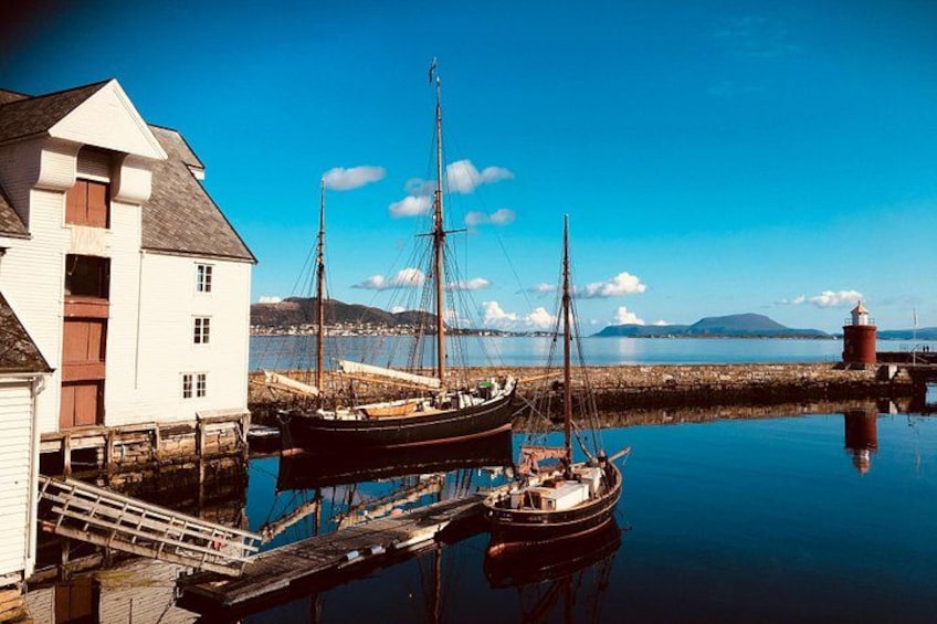 A harbor with boats, a lighthouse, and a white building. 1