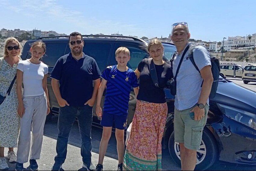 A group of people standing in front of a vehicle on a sunny day. 3