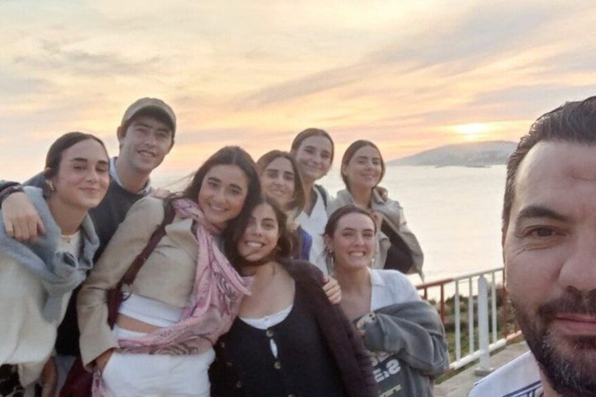 A group of people standing by a railing with a sunset in the background. 4