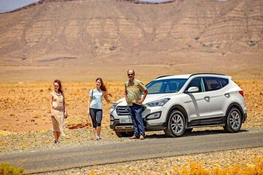 A white SUV parked on a road with a desert landscape in the background. 1