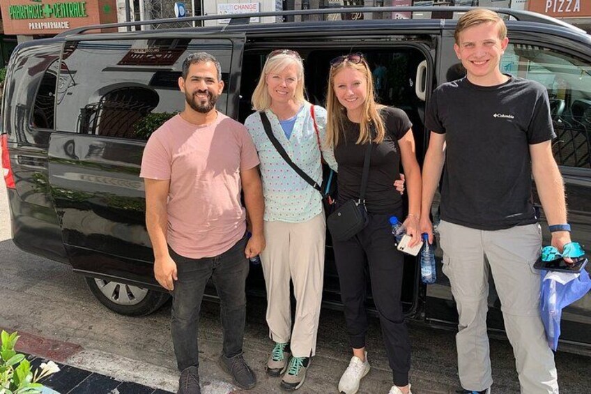 Four people standing in front of a black van with a pizza advertisement on the side. 2