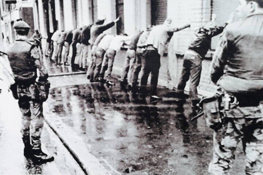 Soldiers in uniform standing in a line on a wet street. 5