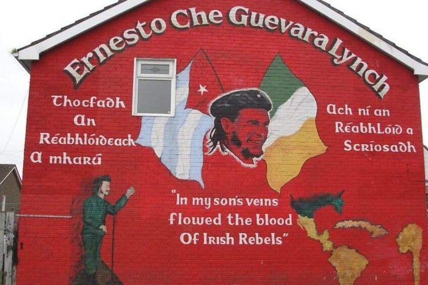 Une fresque murale représentant un homme tenant un pistolet, des drapeaux irlandais et un texte en irlandais. 5