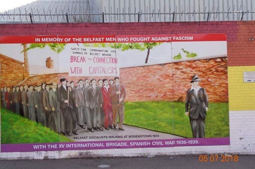 Et mural der mindes Belfasts mænd, som kæmpede mod fascisme, med en gruppe mænd i jakkesæt og én i en rød jakke. 5