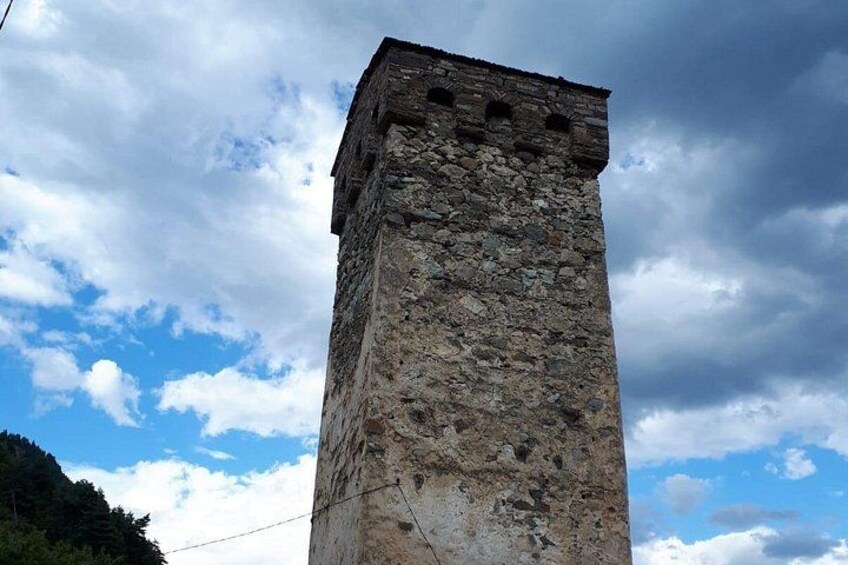 A tall stone tower with a weathered appearance, set against a partly cloudy sky. 3