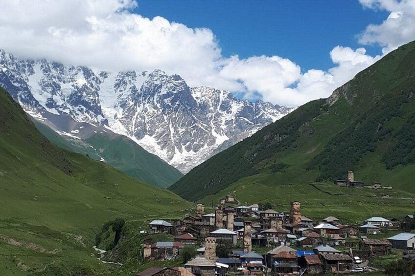 A village nestled in a valley with snow-capped mountains in the background. 4