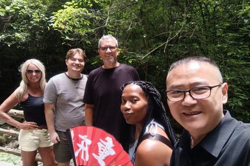 A group of people outdoors with dense foliage in the background. 2