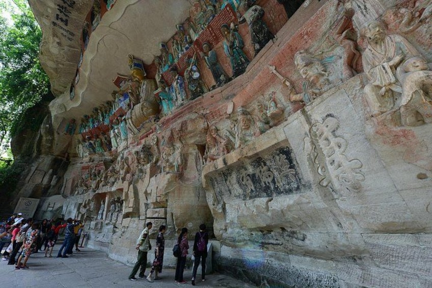 Une vaste paroi rocheuse richement sculptée, ornée de nombreuses statues et de motifs complexes, et entourée de visiteurs. 3