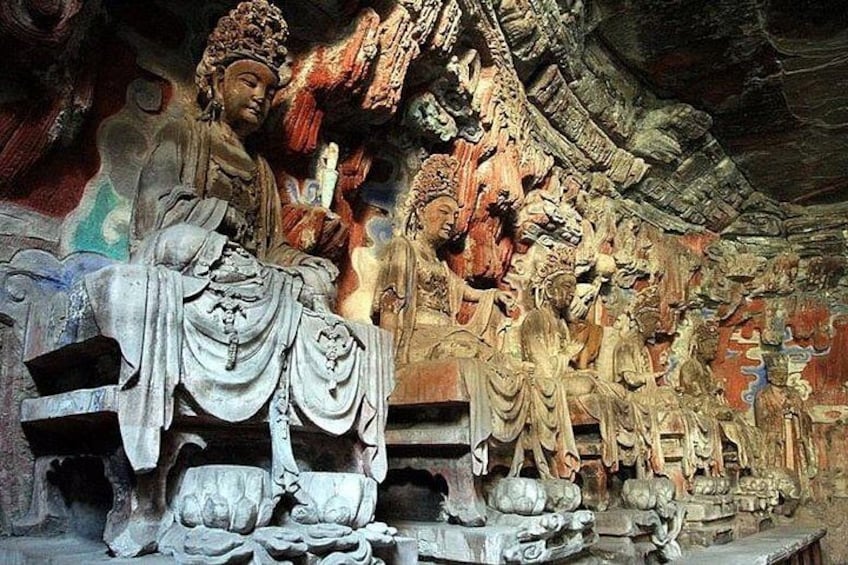 Une sculpture détaillée dans la pierre représentant une figure assise, possiblement une divinité, entourée de figures plus petites et d’éléments architecturaux complexes. 2