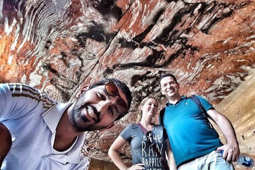 Three people standing in front of a rock formation. 3