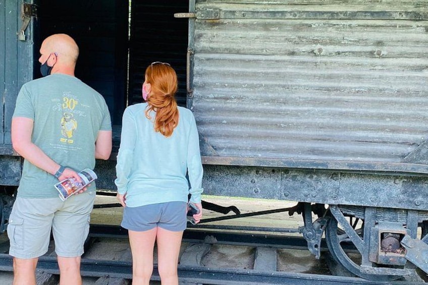 Two people standing on train tracks with a train door open behind them. 3