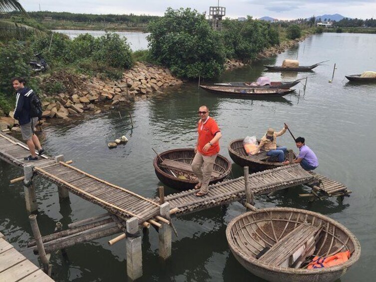 Un muelle de madera que se adentra en un río, con gente de pie y sentada. 1