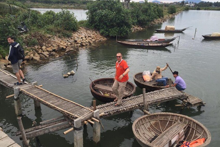 Un pont en bois enjambant une rivière, avec des personnes dessus et des bateaux sur l’eau. 2