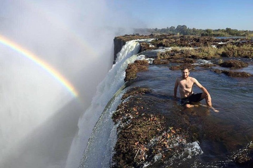 A waterfall, a rainbow, and a person in a natural setting. 5