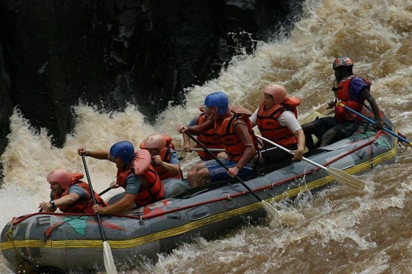 A group of people in a raft navigating through a river with rapids. 3