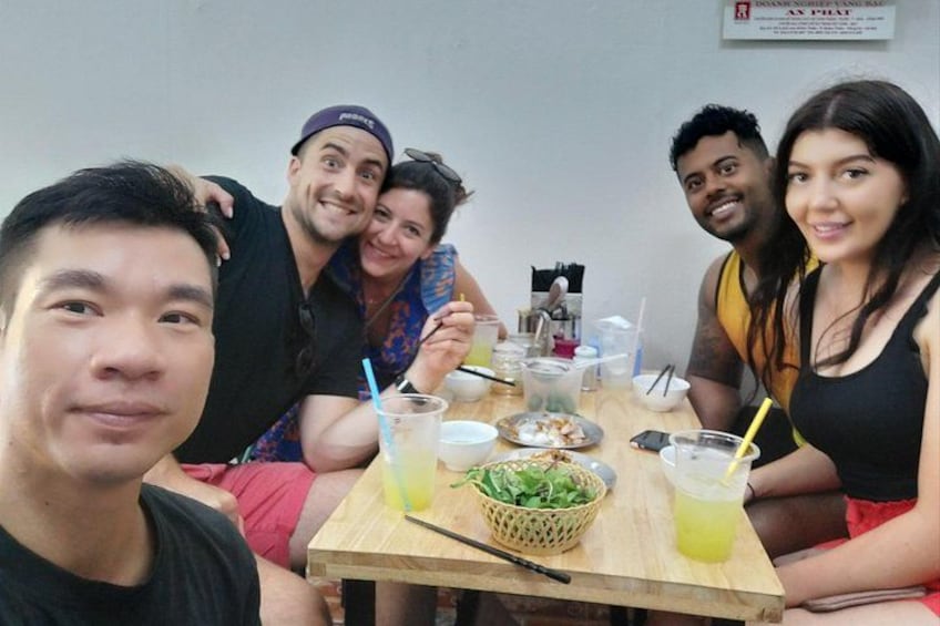 A group of people sitting around a table with food and drinks. 3