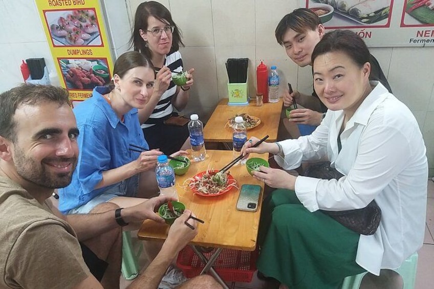 Eine Gruppe von Menschen sitzt an einem Tisch mit Essen, Wasserflaschen und Essstäbchen. 3