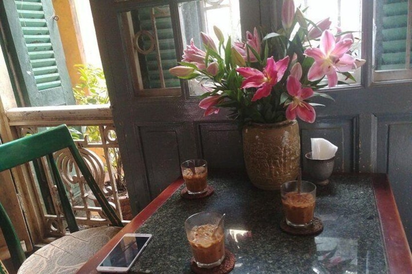 A table with drinks, a vase of flowers, and a chair. 3