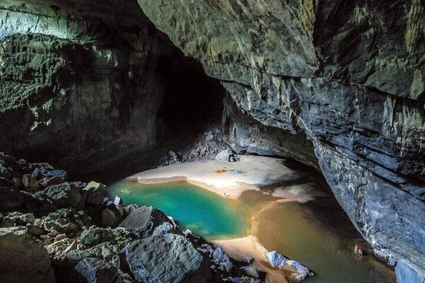 Una cueva con una piscina natural y una persona de pie en la orilla. 1