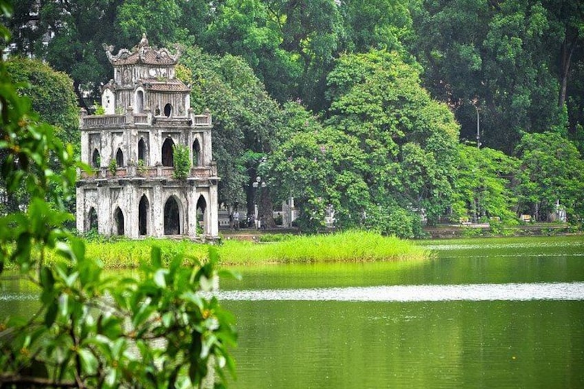 Un templo histórico con múltiples arcos, rodeado de vegetación exuberante y un lago tranquilo. 4
