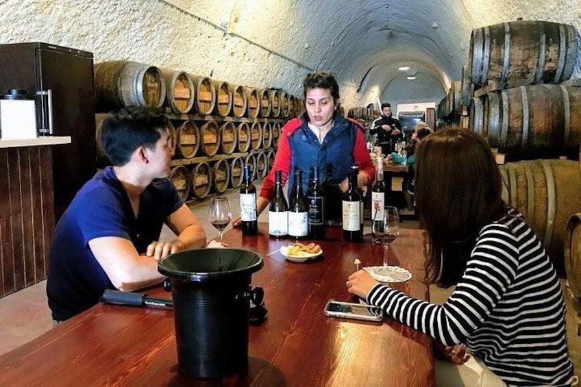 A group of people dining in a cellar with wine barrels in the background. 4