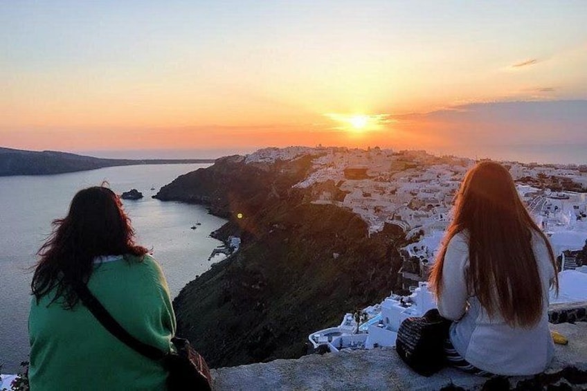 Two people sitting on a cliff overlooking a coastal landscape during sunset. 5